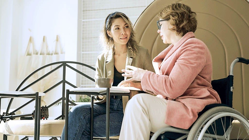 Zwei Frauen im Gespräch, eine davon sitzt im Rollstuhl
